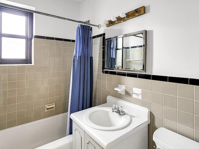 full bath with toilet, shower / bath combo with shower curtain, vanity, and tile walls