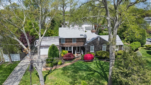 rear view of property featuring a garage, concrete driveway, and a lawn