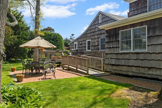 view of grassy yard with a wooden deck and a patio area
