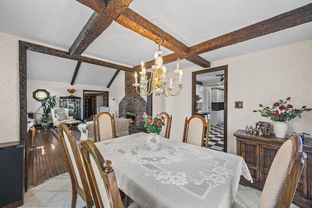 dining area with beamed ceiling, a chandelier, light tile patterned flooring, and a fireplace