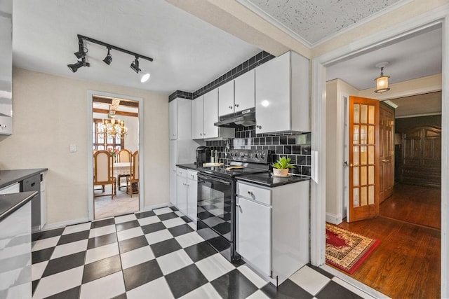 kitchen featuring black electric range oven, dark countertops, white cabinets, under cabinet range hood, and crown molding