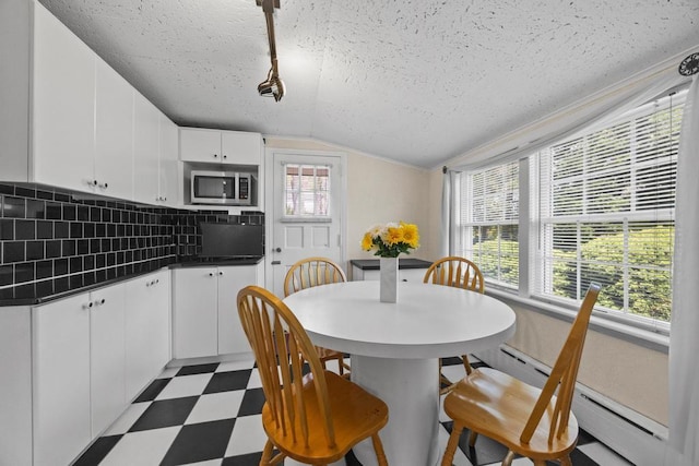 dining area featuring tile patterned floors, a textured ceiling, and lofted ceiling