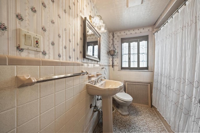 full bathroom featuring radiator, toilet, wallpapered walls, wainscoting, and tile walls