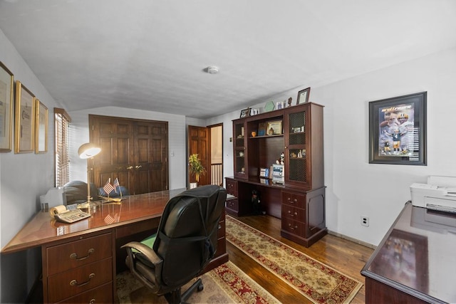office space featuring wood finished floors, built in study area, and lofted ceiling