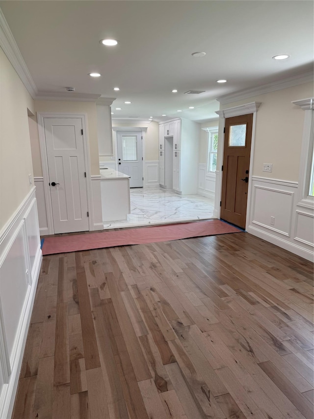 9 Henry St, Wyandanch, NY 11798 - unfurnished living room with crown molding, a decorative wall, a wainscoted wall, and light wood-style flooring
