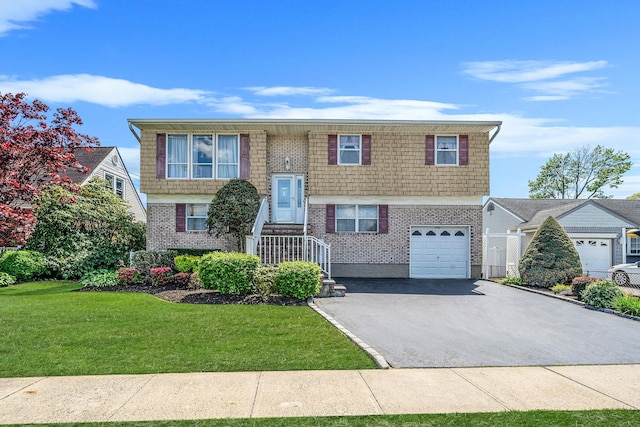 bi-level home with asphalt driveway, a garage, brick siding, and a front yard