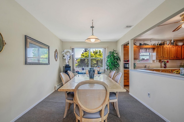 dining area with baseboard heating, healthy amount of natural light, baseboards, and dark colored carpet