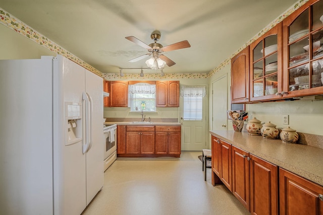 kitchen with white appliances, a sink, glass insert cabinets, ceiling fan, and light countertops