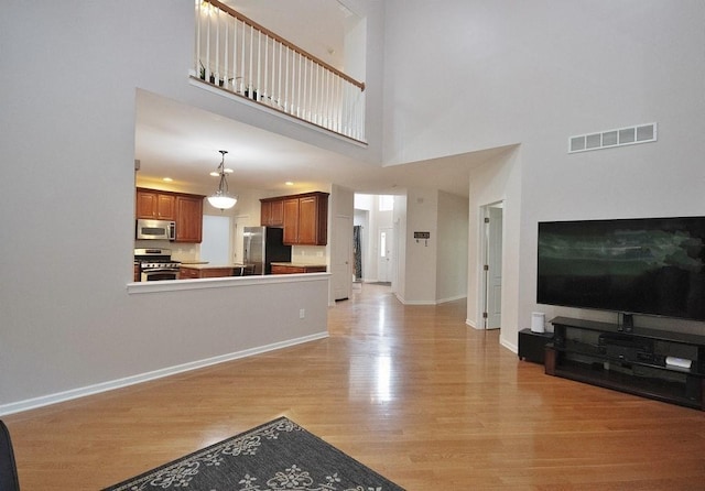 622 Creekside Ln, Fishkill, NY 12524 - unfurnished living room featuring light wood-type flooring, a high ceiling, and baseboards
