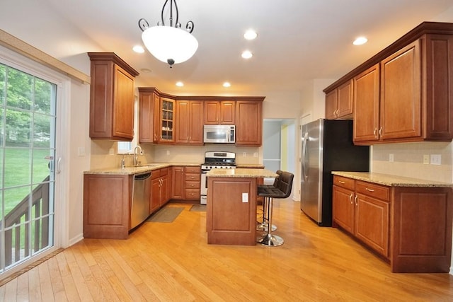 622 Creekside Ln, Fishkill, NY 12524 - kitchen featuring stainless steel appliances, light wood finished floors, a breakfast bar area, brown cabinetry, and backsplash