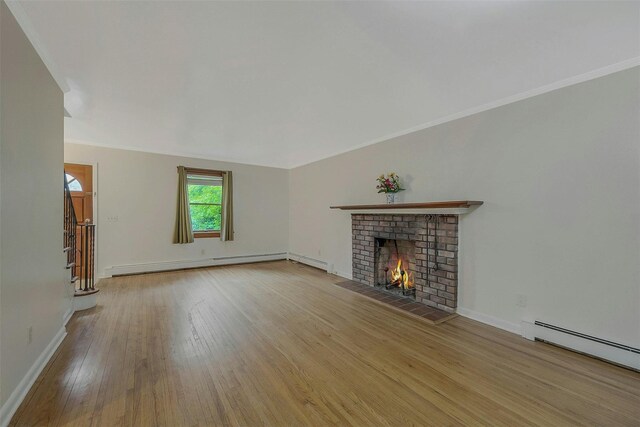 155 Woodbury Rd, Huntington, NY 11743 - unfurnished living room featuring a baseboard heating unit, baseboard heating, wood finished floors, a brick fireplace, and crown molding