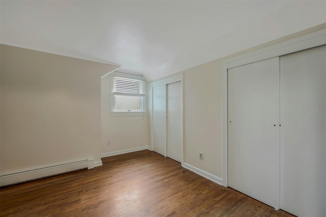 155 Woodbury Rd, Huntington, NY 11743 - unfurnished bedroom featuring multiple closets, a baseboard radiator, wood finished floors, lofted ceiling, and baseboards