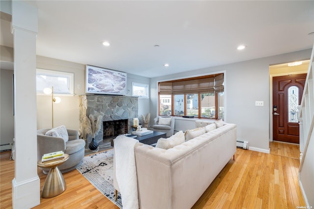 living area with a baseboard heating unit, a fireplace, light wood finished floors, and recessed lighting