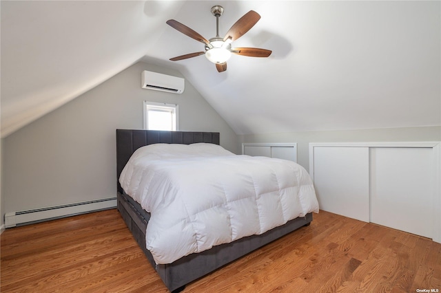 bedroom with a baseboard heating unit, a wall mounted air conditioner, vaulted ceiling, a ceiling fan, and multiple closets