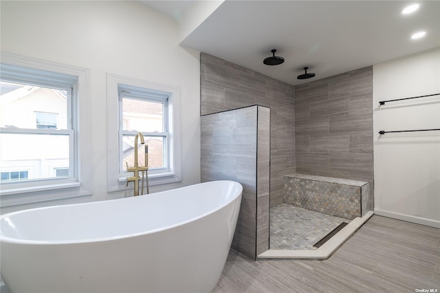 bathroom with a soaking tub, a walk in shower, wood finished floors, and recessed lighting