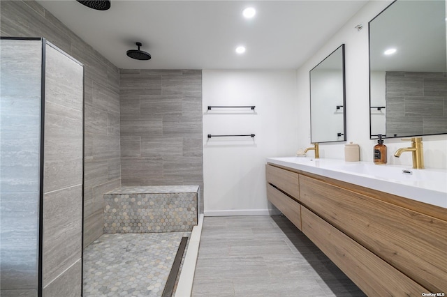 bathroom with tiled shower, double vanity, recessed lighting, baseboards, and wood finished floors