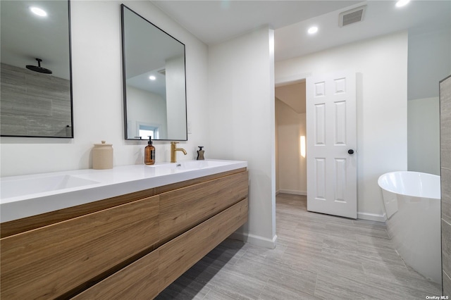 bathroom with a soaking tub, double vanity, baseboards, and recessed lighting