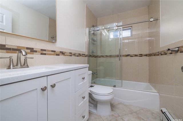 bathroom featuring a baseboard heating unit, tile walls, toilet, bath / shower combo with glass door, and vanity