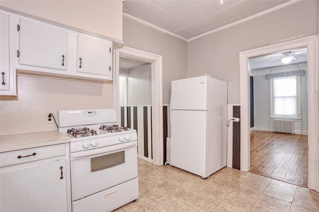 kitchen featuring white appliances, radiator, crown molding, light countertops, and white cabinets