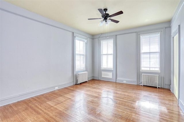 spare room with radiator, light wood-style floors, and a ceiling fan