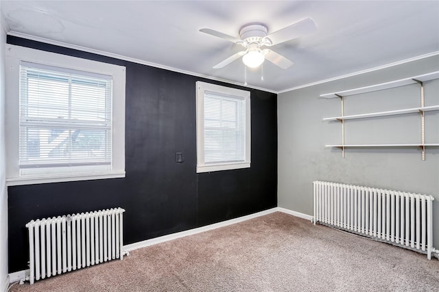 spare room featuring radiator heating unit, carpet floors, a ceiling fan, crown molding, and baseboards