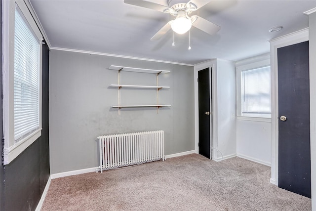 unfurnished bedroom with radiator, carpet, baseboards, ornamental molding, and a ceiling fan