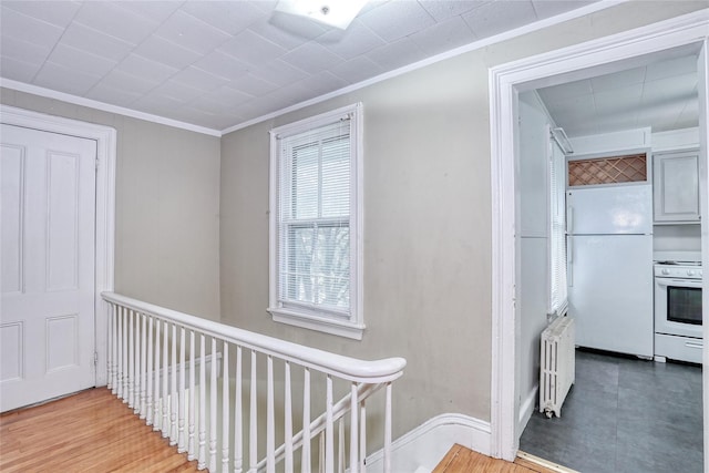 corridor featuring radiator heating unit, ornamental molding, and baseboards