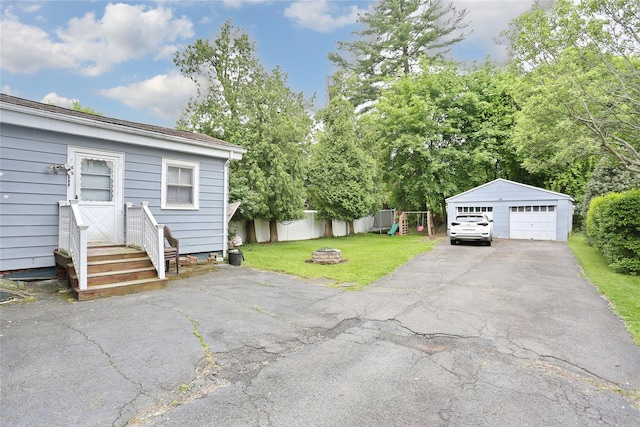 view of yard featuring a detached garage, entry steps, an outdoor structure, and an outdoor fire pit