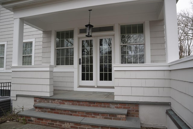 view of exterior entry featuring a porch and central AC unit