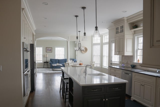 kitchen featuring a sink, open floor plan, arched walkways, decorative columns, and recessed lighting