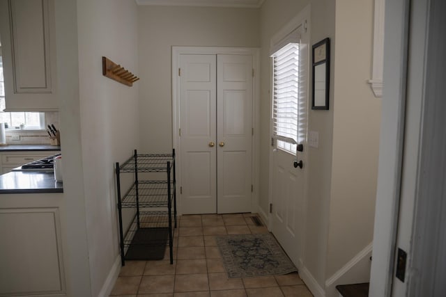 doorway with light tile patterned flooring and baseboards