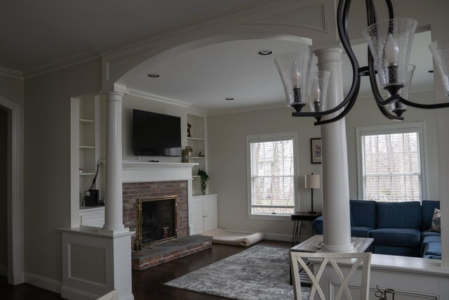 living room with ornate columns, dark wood-style floors, a brick fireplace, arched walkways, and crown molding