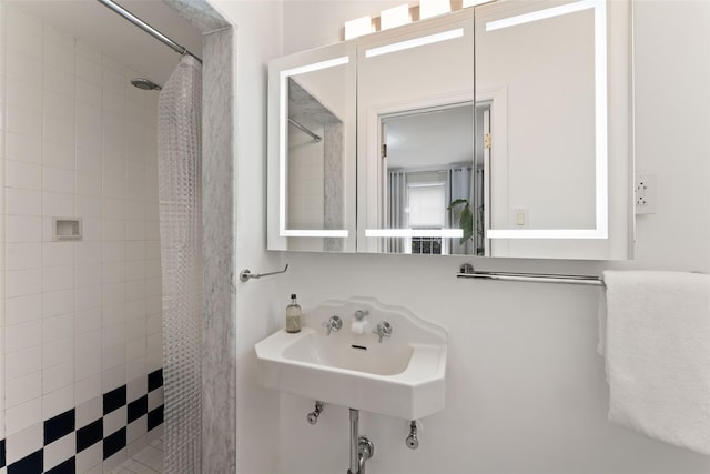 full bath with tiled shower and a sink