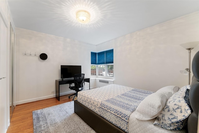 bedroom with wood finished floors, baseboards, and radiator heating unit