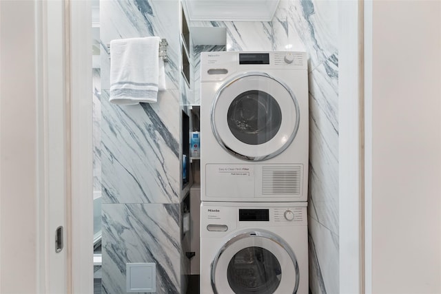 laundry area with stacked washing machine and dryer and tile walls