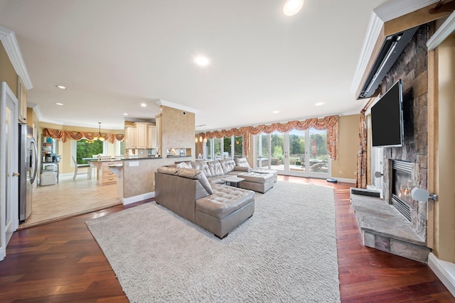 9 Fairwind Ct, Oakdale, NY 11769 - living room featuring a stone fireplace, ornamental molding, baseboards, wood finished floors, and recessed lighting