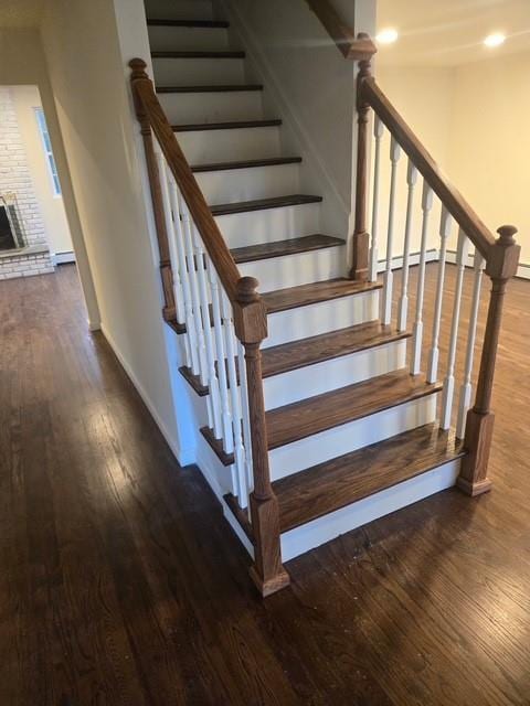 stairs with wood finished floors, baseboards, and baseboard heating