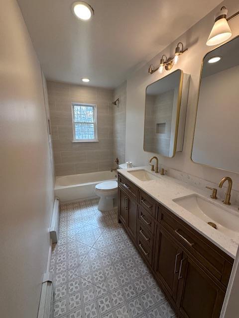 bathroom featuring toilet, shower / bathtub combination, double vanity, and baseboard heating