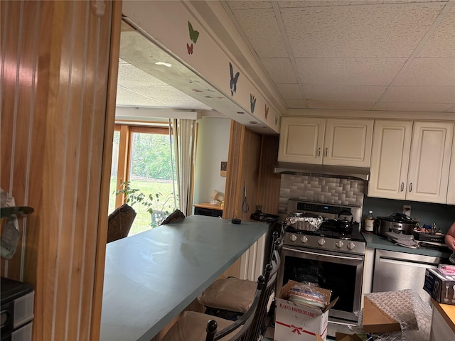 6 Annette Ln, East Moriches, NY 11940 - kitchen featuring stainless steel range with gas stovetop, a paneled ceiling, white cabinetry, dark countertops, and a kitchen bar
