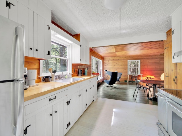 60 Park Road Ext, Eldred, NY 12792 - kitchen featuring freestanding refrigerator, wood walls, a sink, light countertops, and white cabinetry