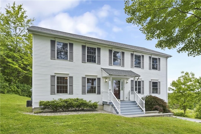 colonial house featuring a front lawn and central AC unit