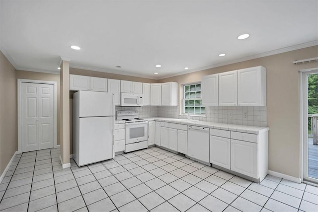 kitchen featuring white appliances, decorative backsplash, white cabinets, crown molding, and tile counters