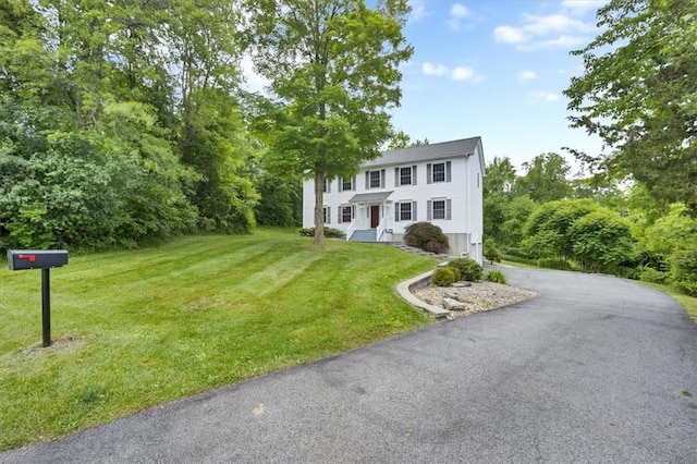 colonial-style house featuring driveway and a front yard
