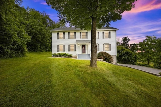 colonial-style house featuring a front lawn and concrete driveway