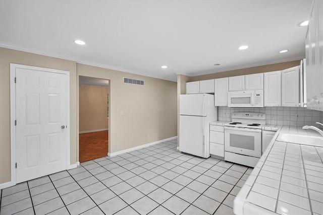 kitchen featuring white appliances, tile counters, a sink, white cabinets, and tasteful backsplash
