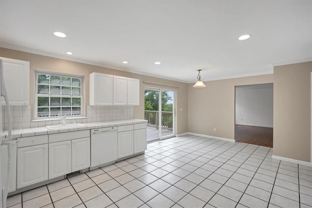 kitchen featuring dishwasher, tasteful backsplash, white cabinetry, ornamental molding, and tile counters