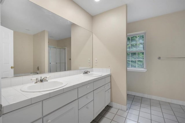 full bathroom featuring a stall shower, double vanity, baseboards, and tile patterned floors