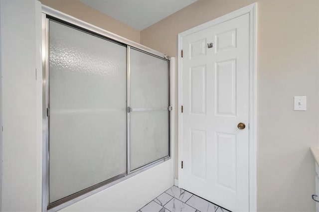 bathroom featuring marble look tile flooring and enclosed tub / shower combo