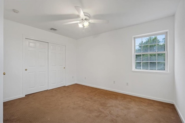 unfurnished bedroom with carpet flooring, a closet, baseboards, and ceiling fan