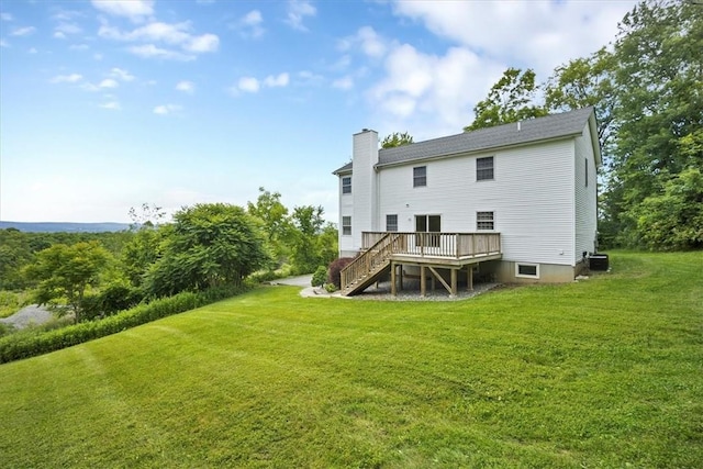 back of property with stairway, a chimney, a wooden deck, and a lawn
